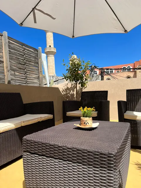 Terrazza: salotto in rattan sotto l'ombrellone, sullo sfondo il minareto