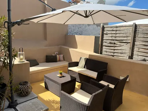 Terrazza: vista d'insieme del salotto esterno con divanetti in muratura, poltrone in rattan e ombrellone