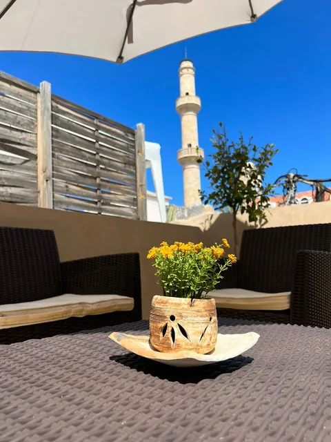 Terrazza: tavolino con fiori gialli, sullo sfondo il minareto