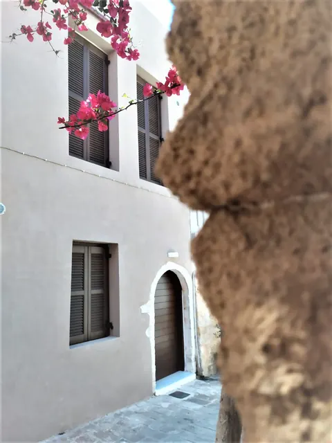 Facciata chiara con porta ad arco e bouganville