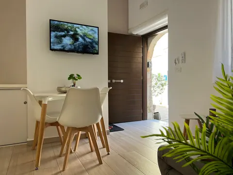 Soggiorno: tavolo da pranzo, TV a parete e porta d'ingresso