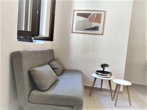 Soggiorno: divano grigio con tavolini, quadro e finestra con persiane