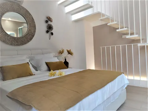Camera: letto matrimoniale, specchio rotondo e scala sospesa
