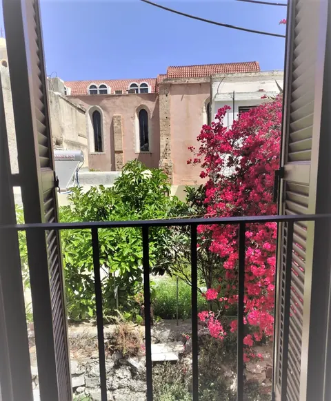 Vista dal balcone: chiesa in pietra, alberi e bouganville